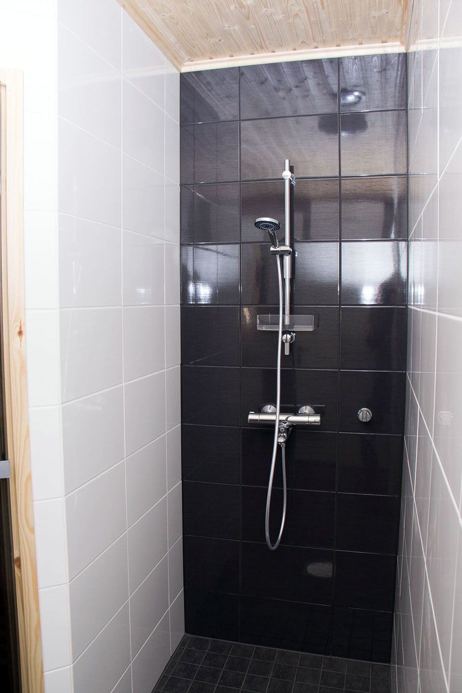 Mustaa ja valkoista laatoitusta yhdistelevä suihkutila