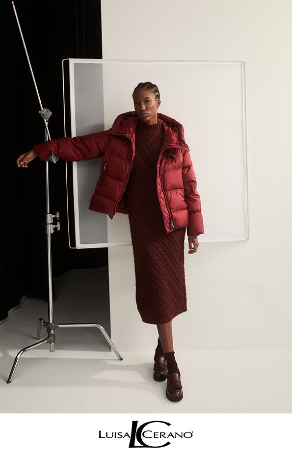 Frau in burgunderfarbener Pufferjacke und Kleid in einem Studio.