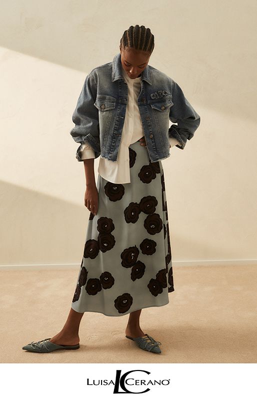 Frau in Jeansjacke, geblümtem Rock und flachen Schuhen; Innenaufnahme.