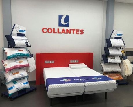 Expositor de colchones con el logotipo de Collantes, estructura de cama roja y almohadas apiladas a ambos lados