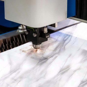 Una máquina está cortando un trozo de granito con una manguera conectada a ella.