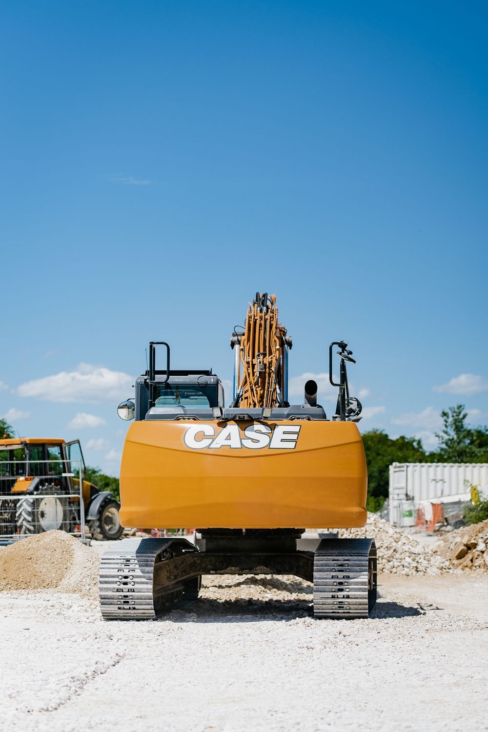 Excavatrice orange Case sur un chantier de construction sous un ciel bleu