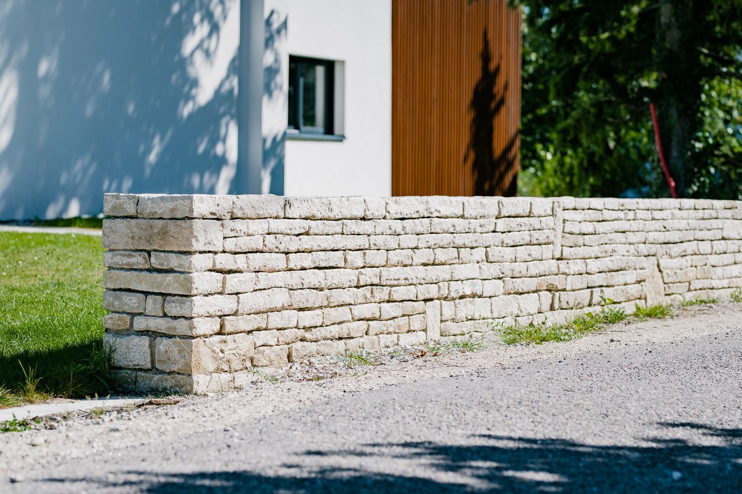 Mur de soutènement en briques de pierre devant une maison moderne blanche et marron