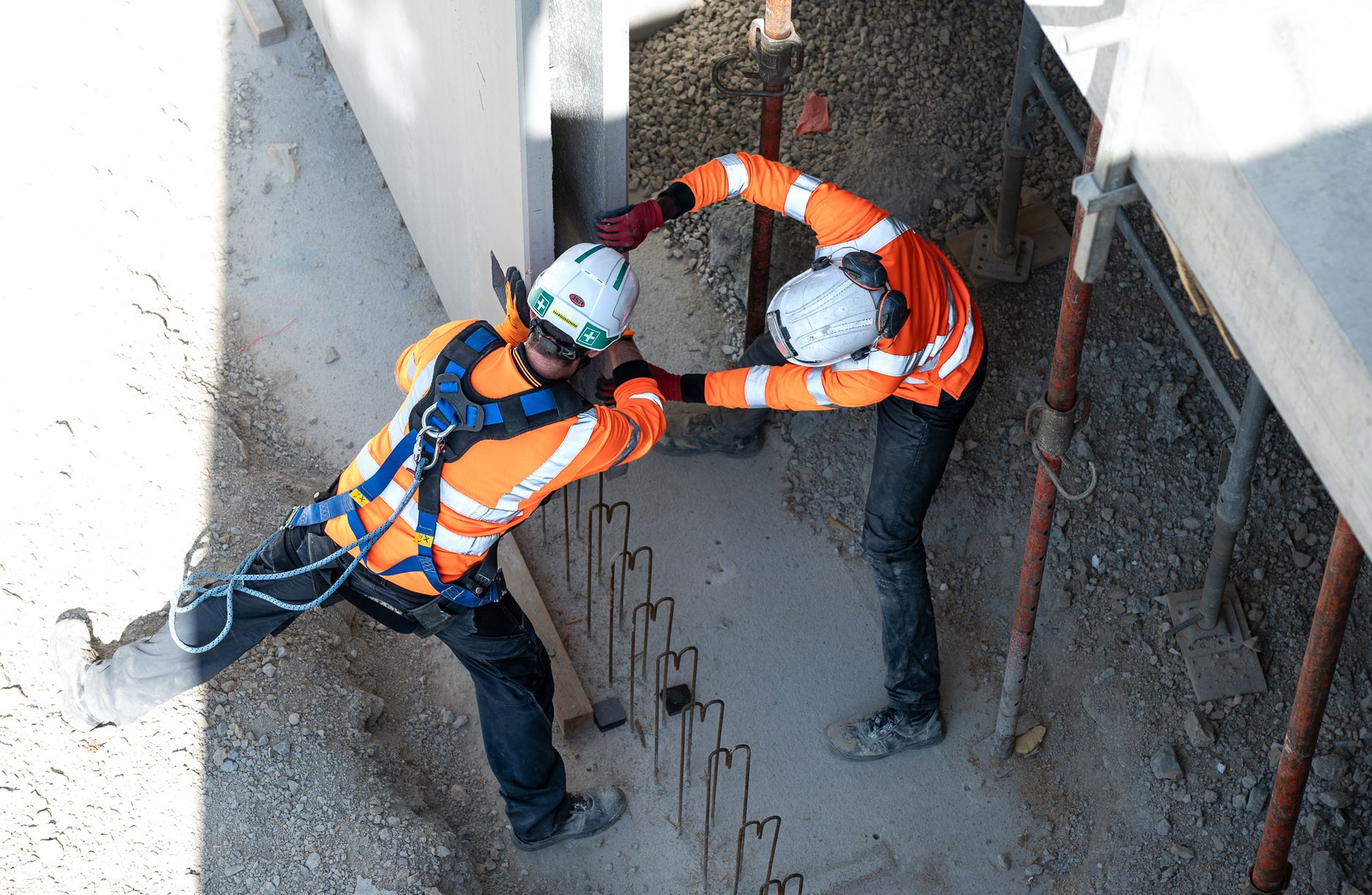 Deux ouvriers du bâtiment portant un gilet orange et un casque de chantier