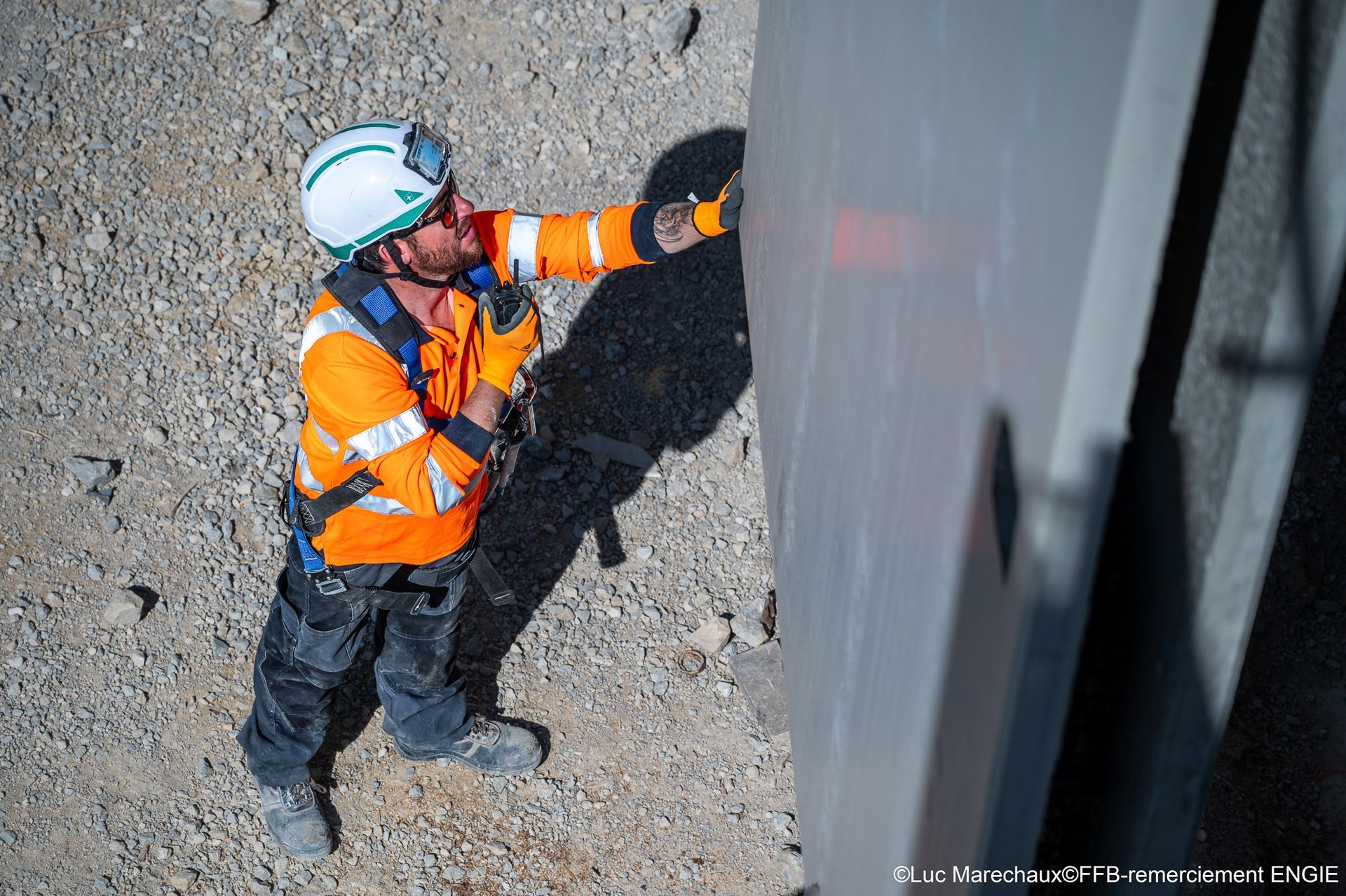 Un ouvrier du bâtiment en équipement de sécurité inspecte un mur à l'extérieur