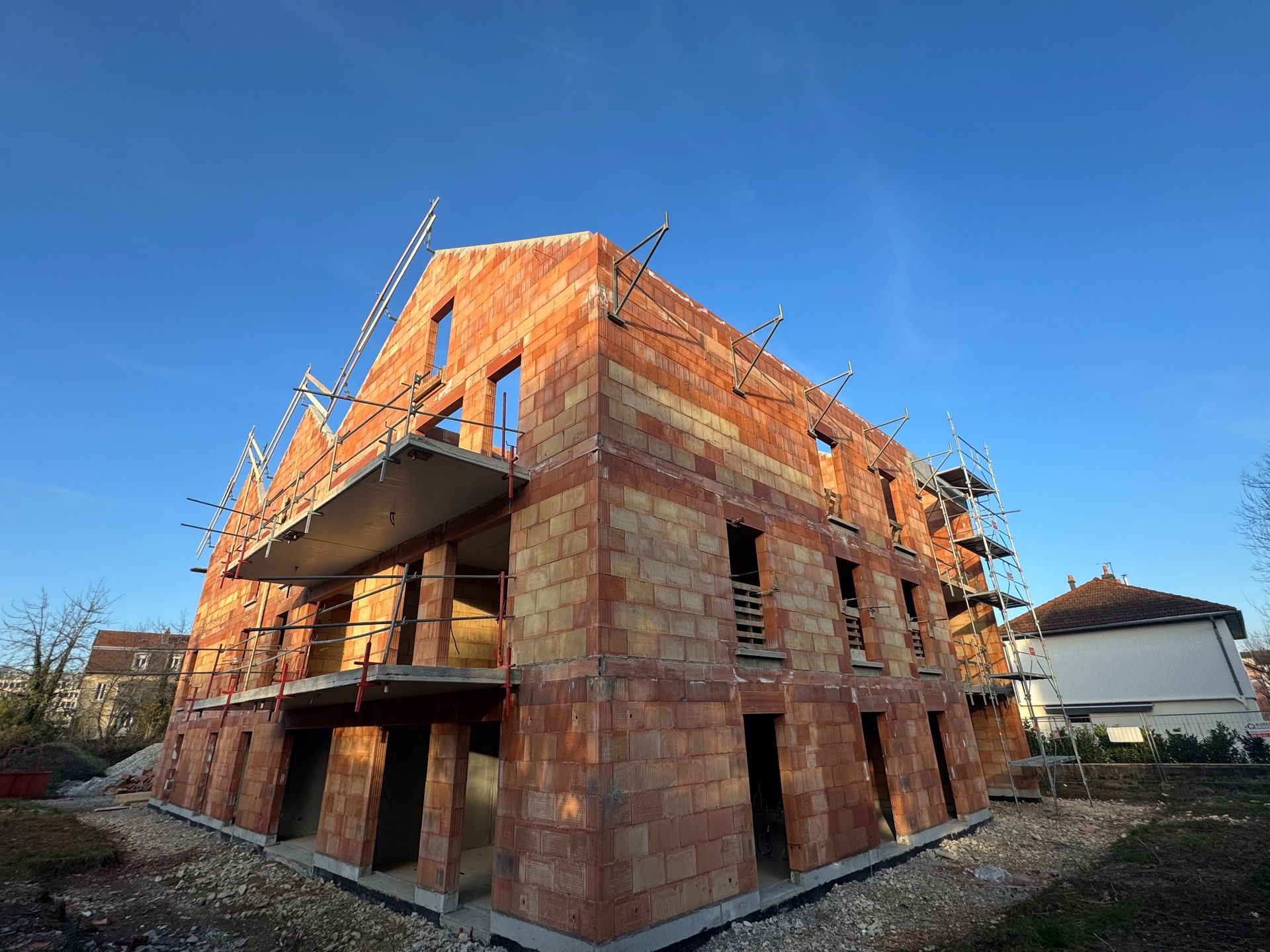 Bâtiment en construction : murs en briques rouges, échafaudages