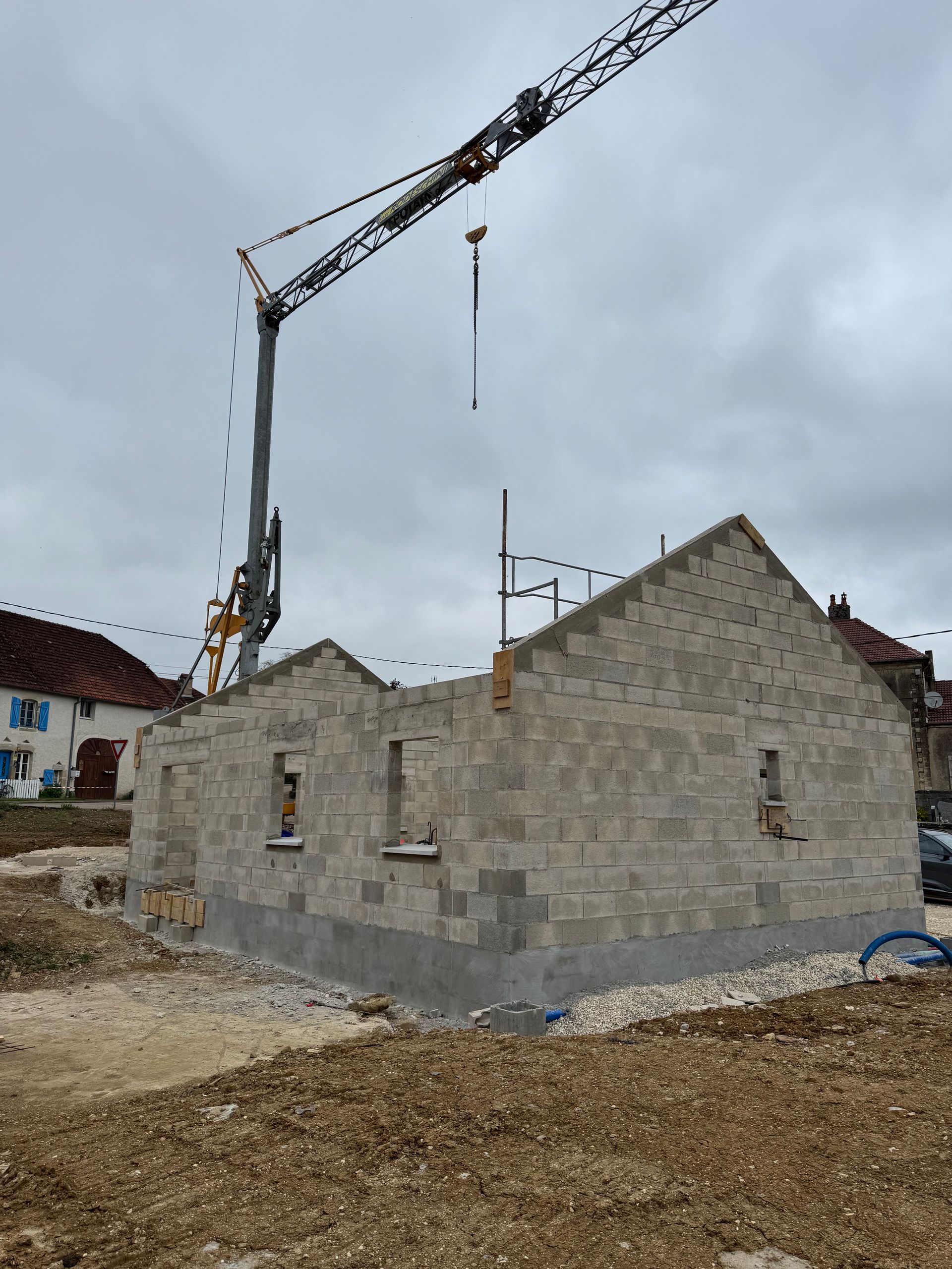 Construction d'un bâtiment en blocs gris avec une grue