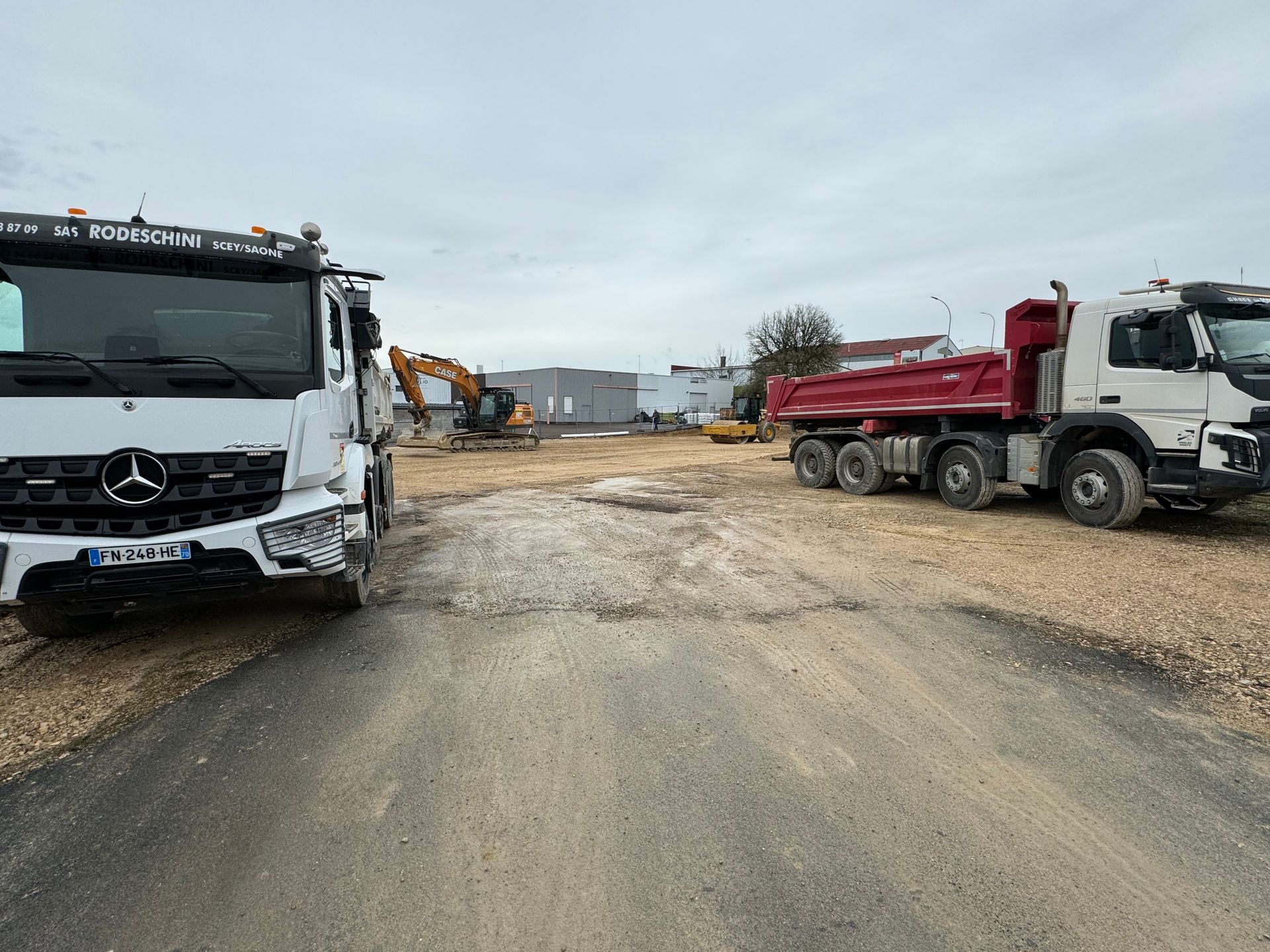 Chantier de construction avec camions, excavatrice et terrain en gravier