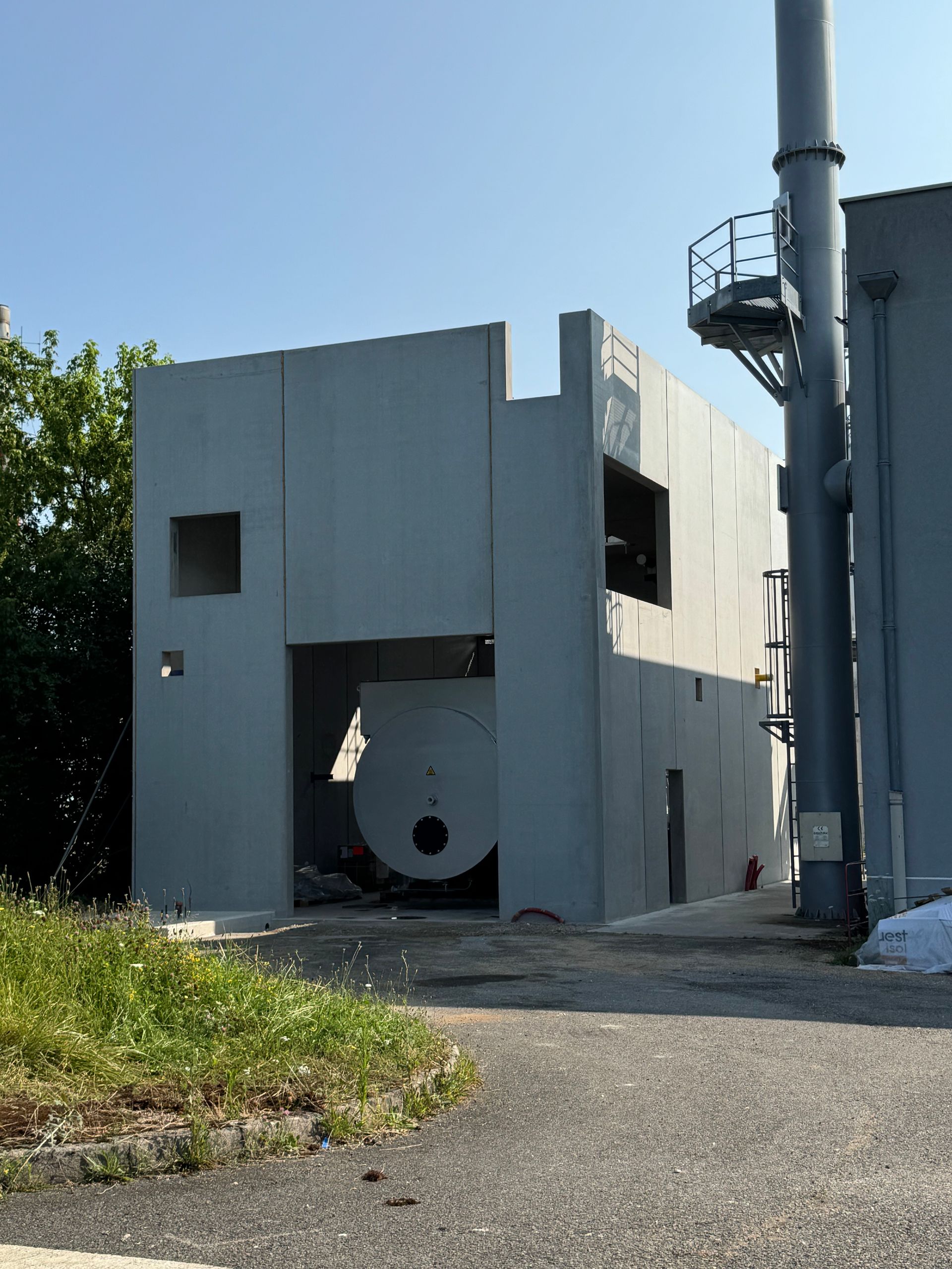 Bâtiment industriel gris avec structure circulaire visible à l'intérieur