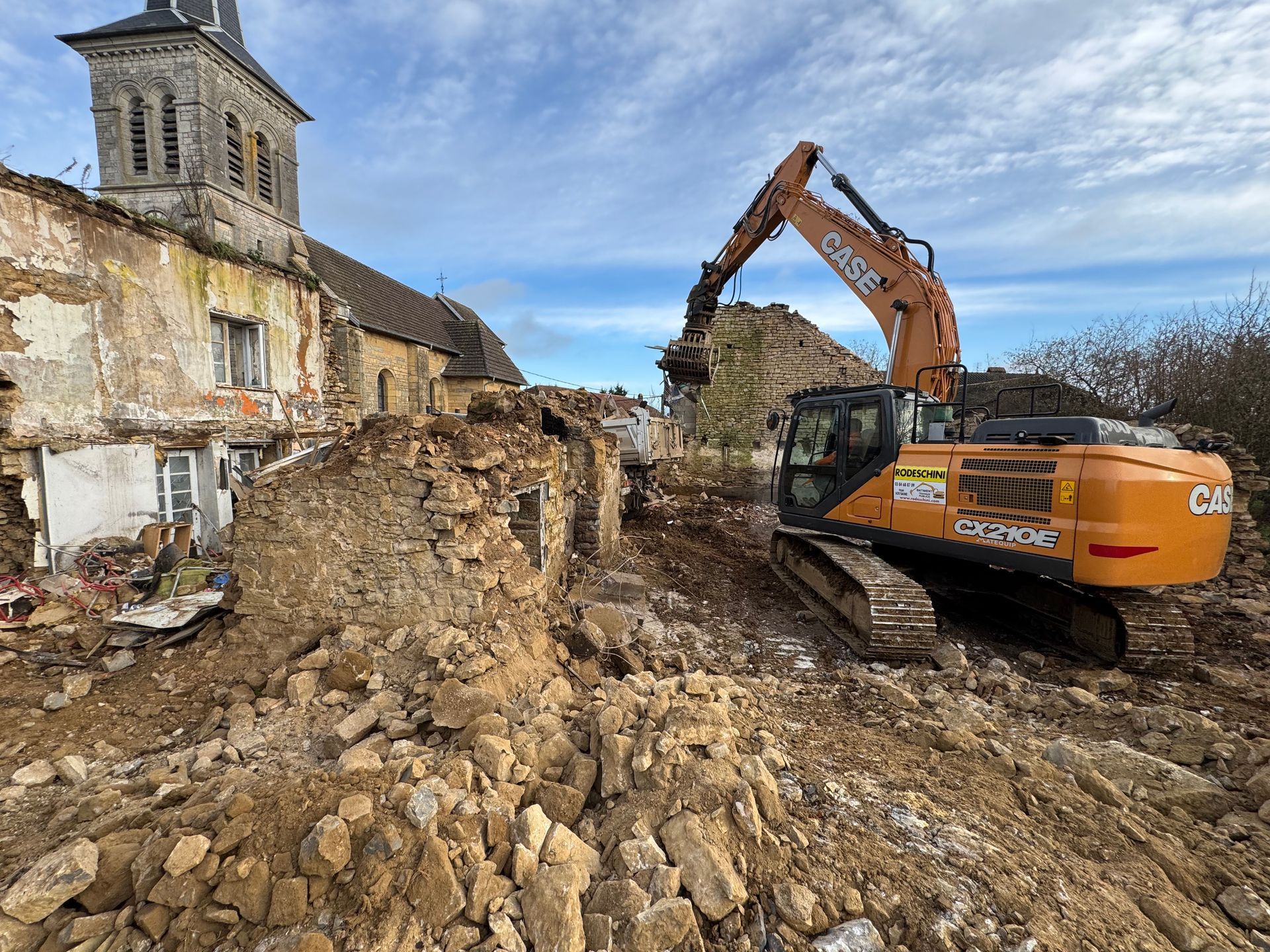 Une excavatrice démolit un bâtiment en pierre