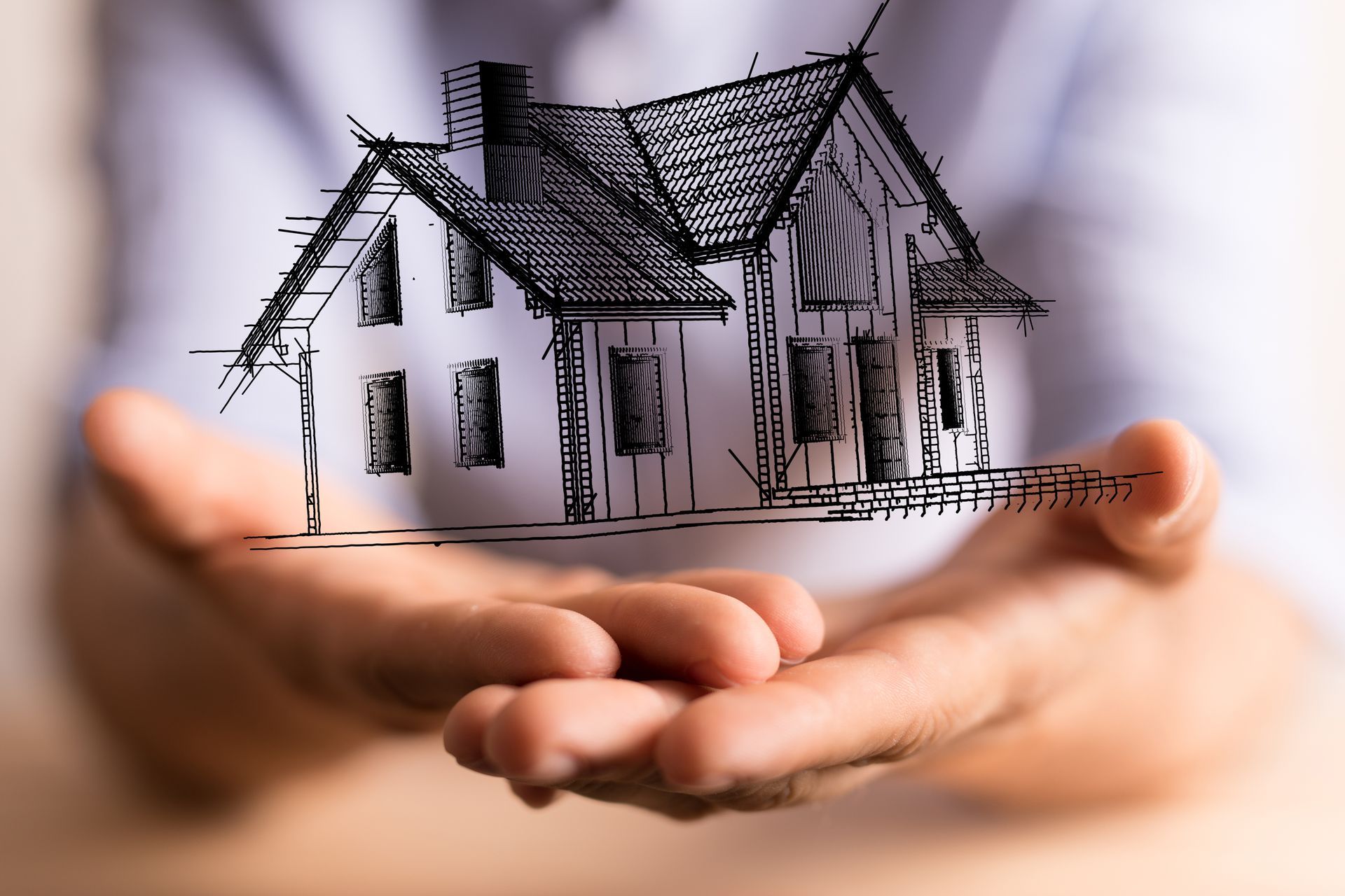 Des mains tenant un croquis d'une maison au toit sombre
