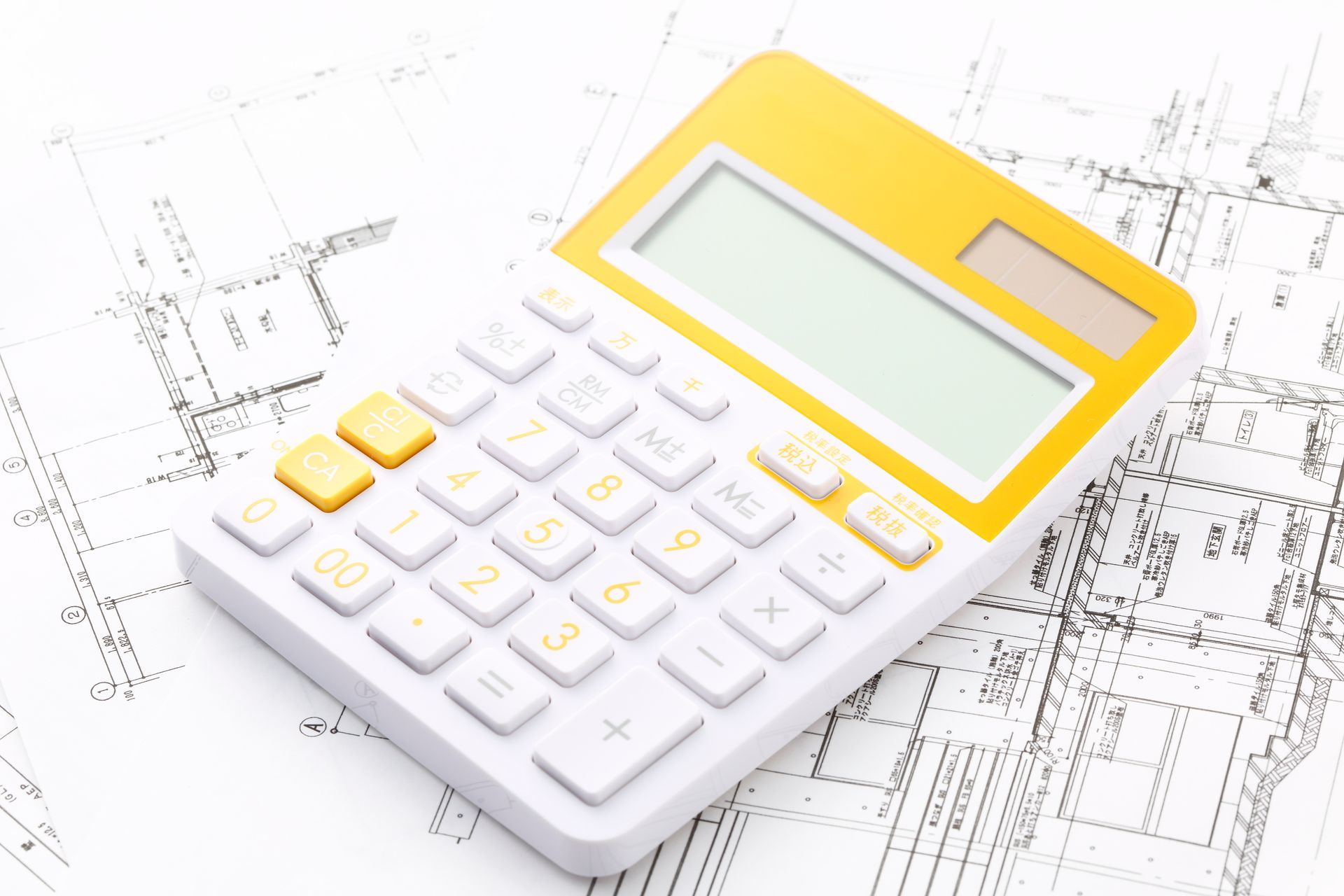 Calculatrice blanche à touches jaunes sur des plans et schémas architecturaux