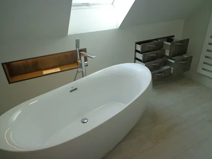 Salle de bains moderne avec un plan de travail rouge, des armoires blanches et un grand miroir. Murs carrelés gris.