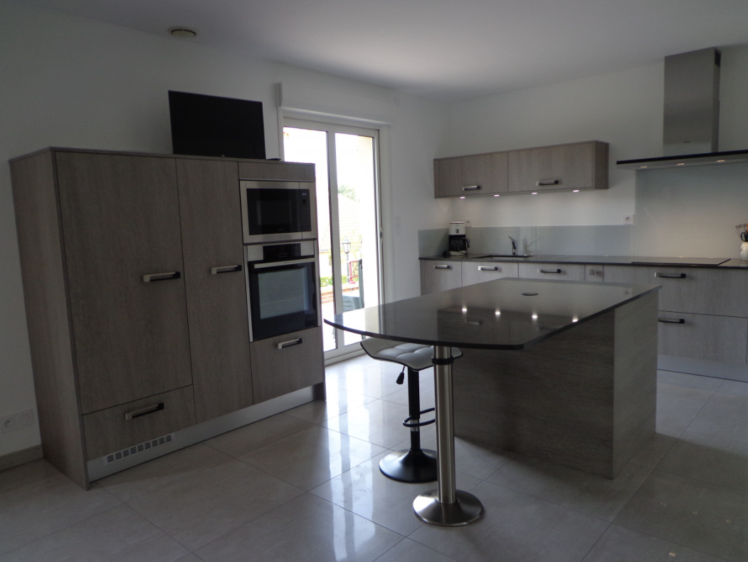 Cuisine moderne avec placards noirs et blancs, rideaux à pois rouges et murs gris.