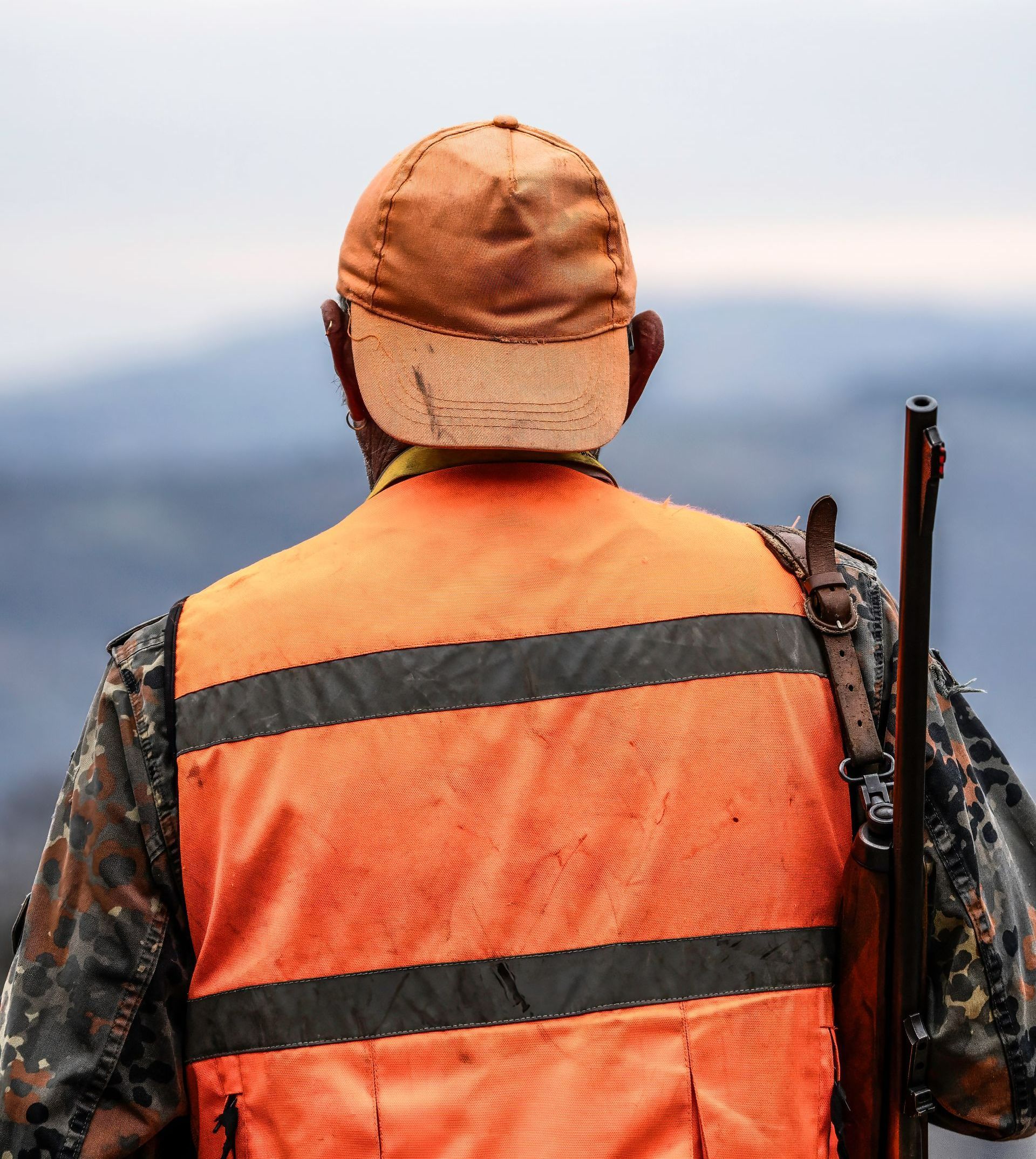 Chasseur de dos avec une casquette et une veste orange