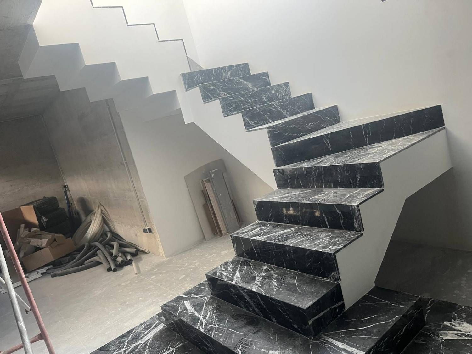 Escalera de mármol negro en un interior sin terminar en construcción.