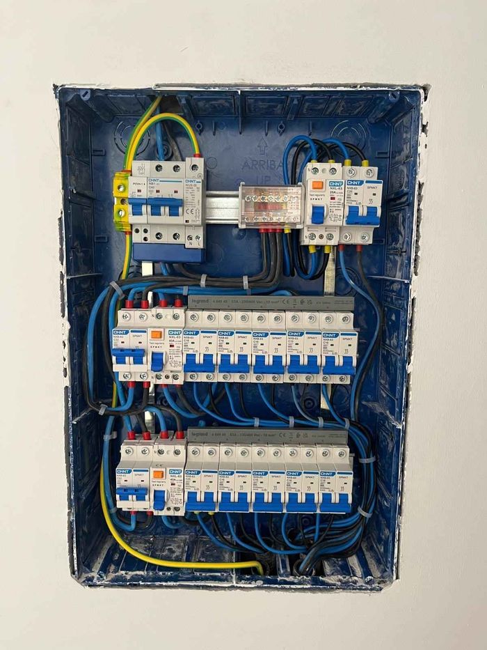 Panel eléctrico con filas de disyuntores y cableado dentro de una carcasa azul oscuro.