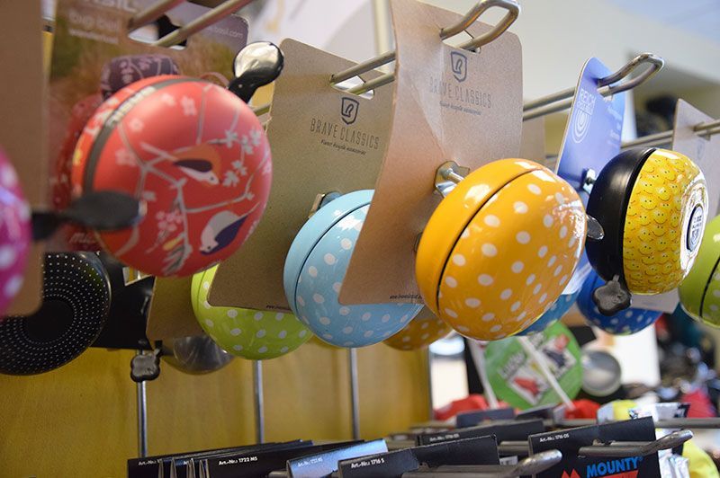 In einem Geschäft hängt ein Haufen Fahrradklingeln an einem Ständer.