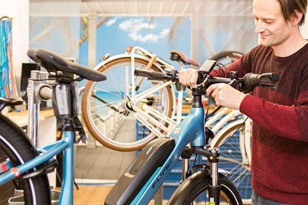 Ein Mann arbeitet in einem Geschäft an einem Elektrofahrrad.