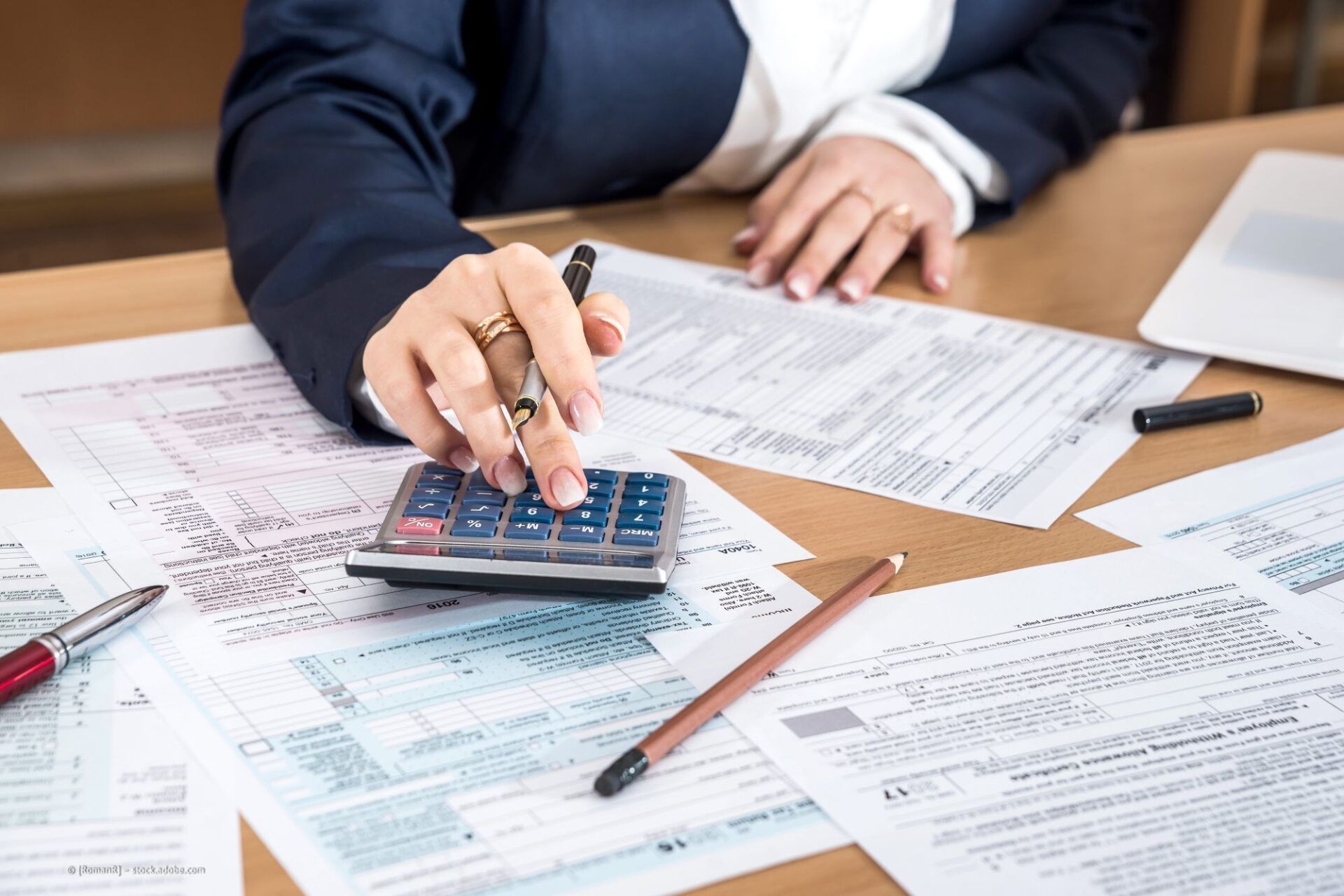 Bild von Person mit Rechner in Hand am Tisch