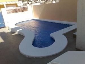 Una pequeña piscina está rodeada por una valla blanca.
