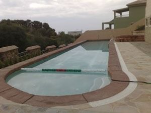 Una gran piscina con una casa al fondo.