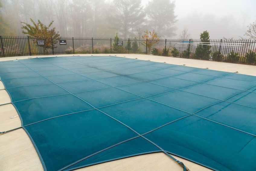 Una gran piscina con una cubierta azul en un día de niebla.
