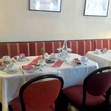 roten Stühle an zwei gedeckten Esstischen im Café