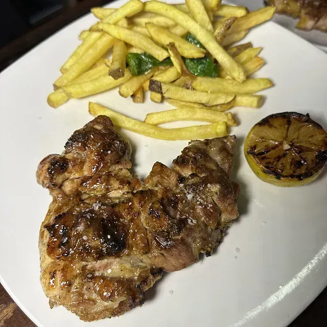 Un plato blanco cubierto con pollo y papas fritas