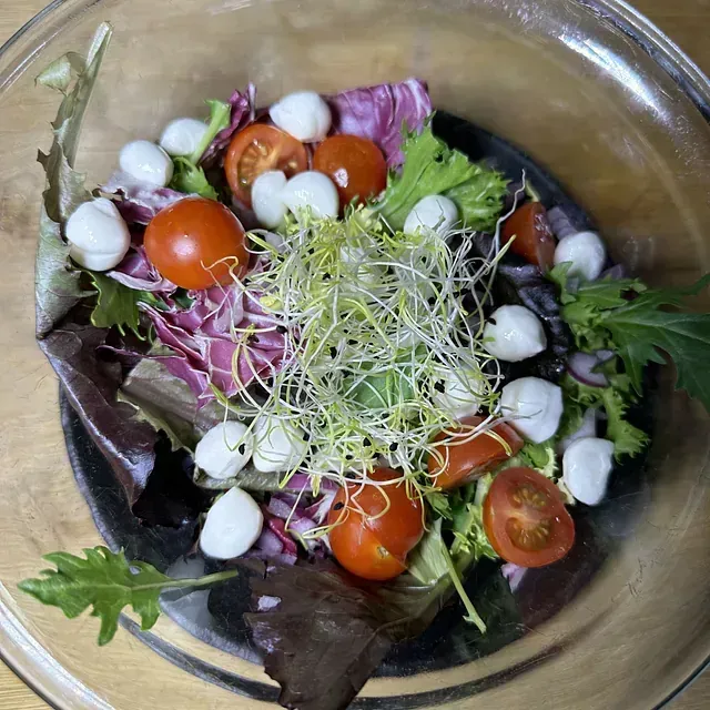 Una ensalada con tomates y mozzarella en un bol de cristal.