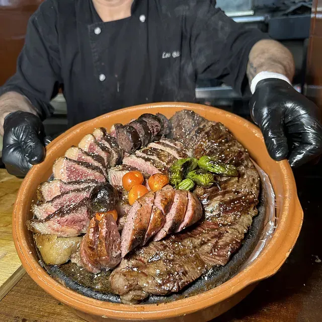 Un chef sostiene un tazón de carne y verduras.