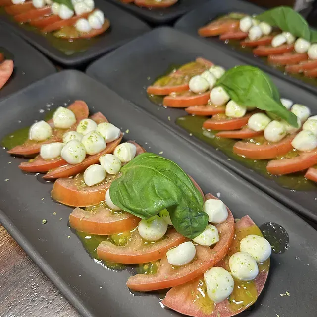 Un primer plano de un plato de comida con tomates y mozzarella sobre una mesa.