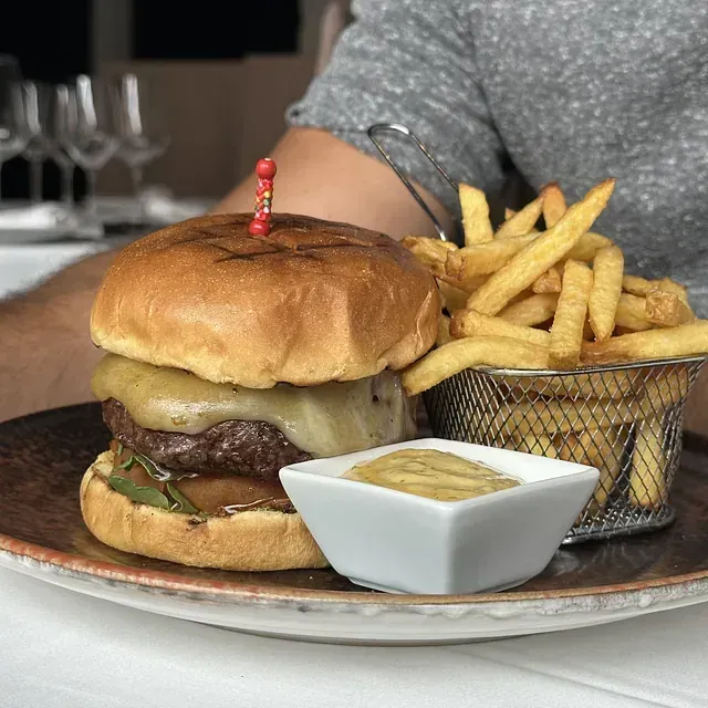 Una hamburguesa y papas fritas en un plato con salsa para mojar