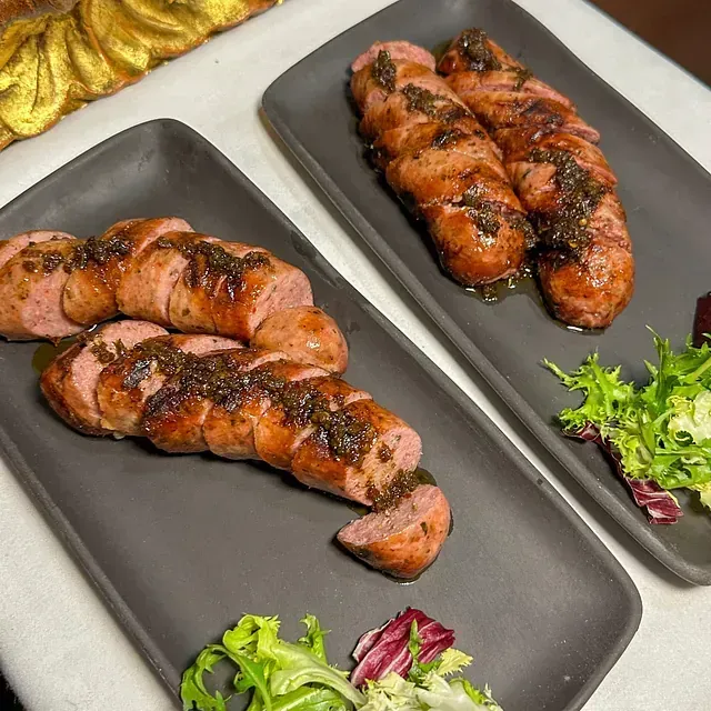 Dos platos negros llenos de salchichas y lechuga sobre una mesa.