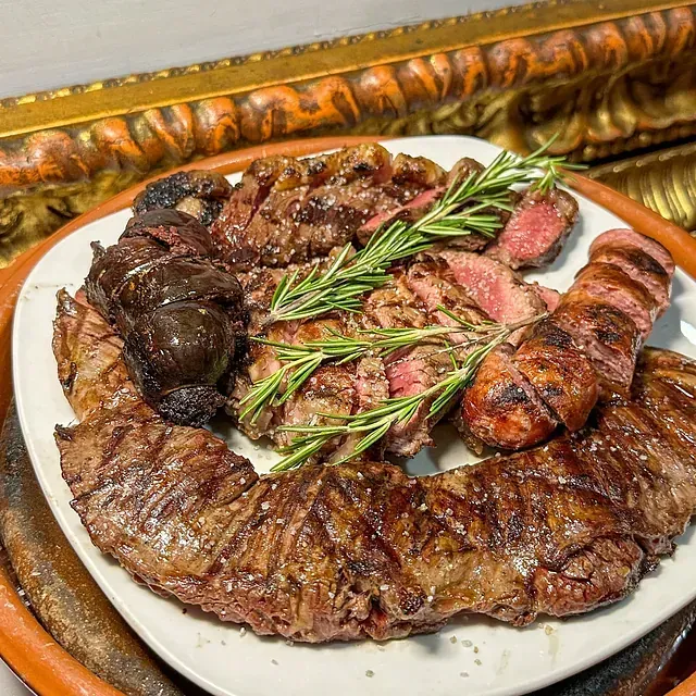 Un plato de carne con romero encima.