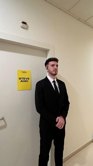 Un hombre con traje y corbata está parado frente a una puerta.
