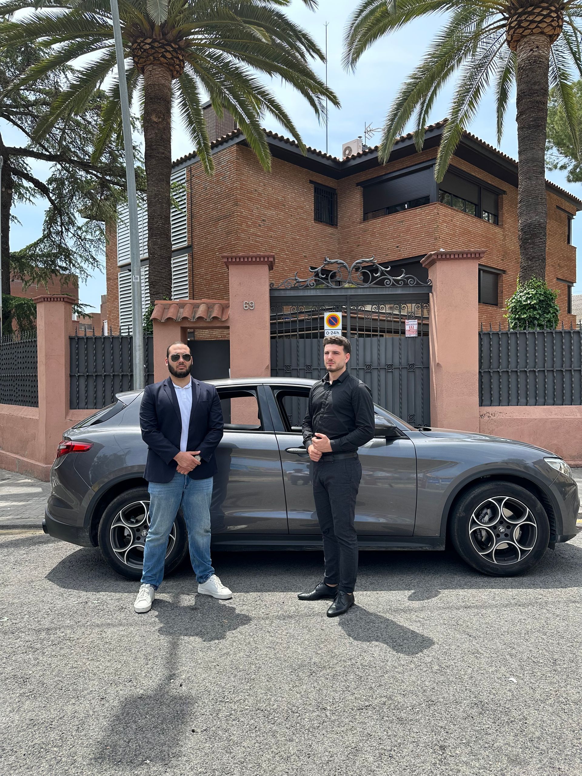 Dos hombres están parados junto a un coche frente a una casa.