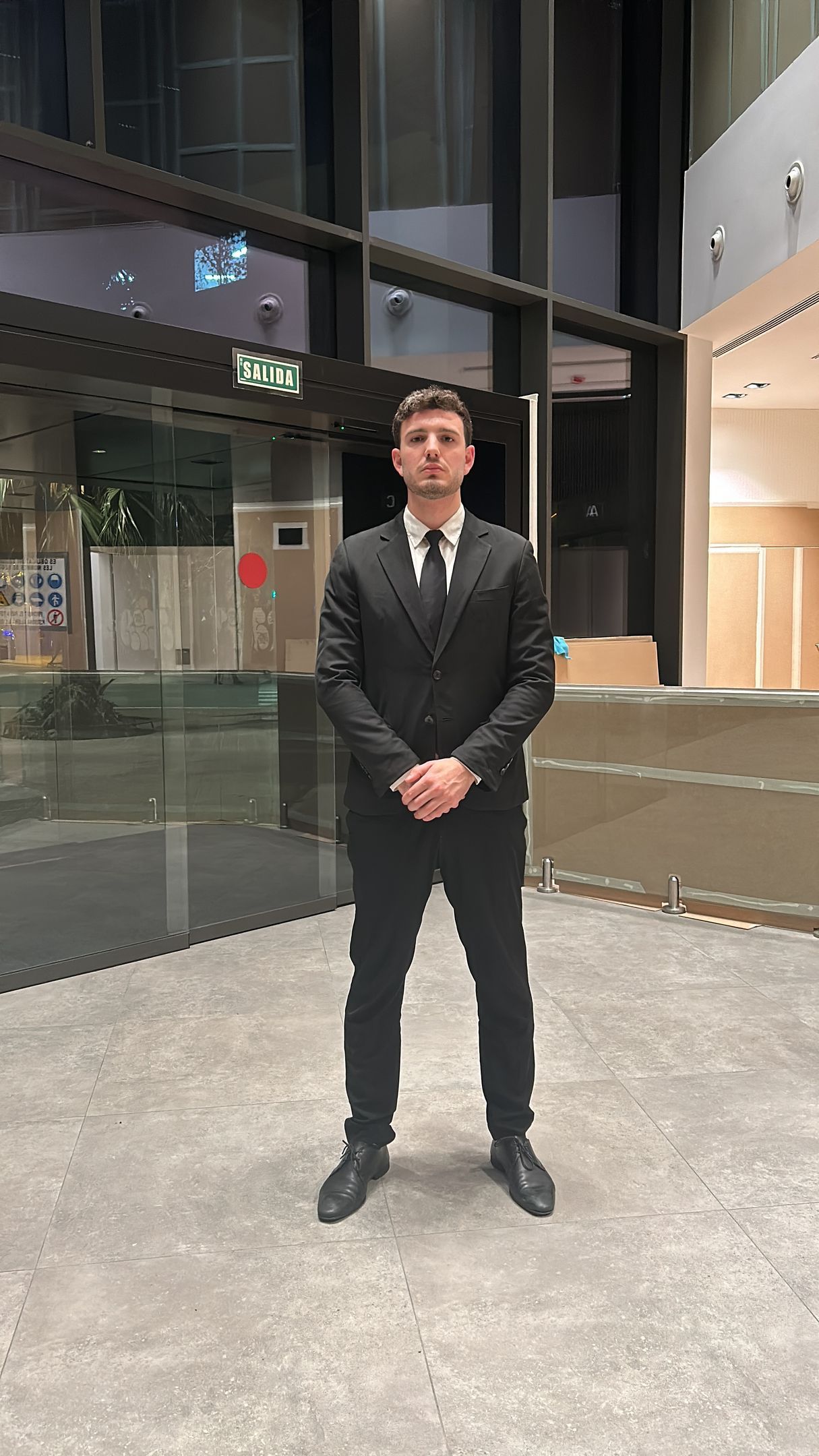 Un hombre con traje y corbata está parado frente a un edificio.