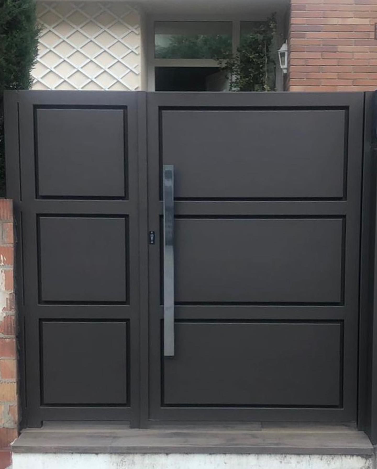Una puerta negra con manija se encuentra frente a un edificio de ladrillos.