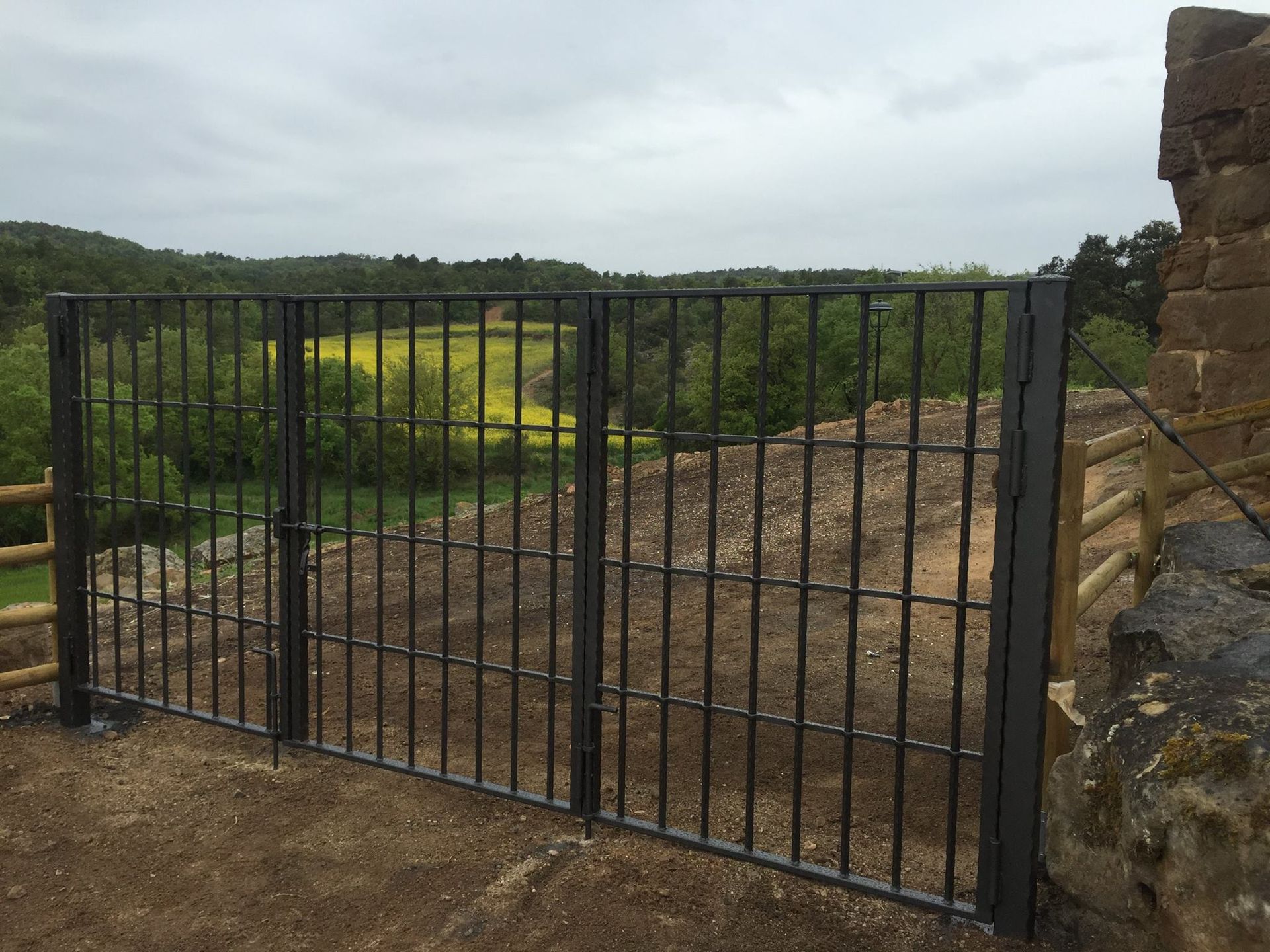 Una puerta de hierro forjado con vista a un campo detrás de ella.