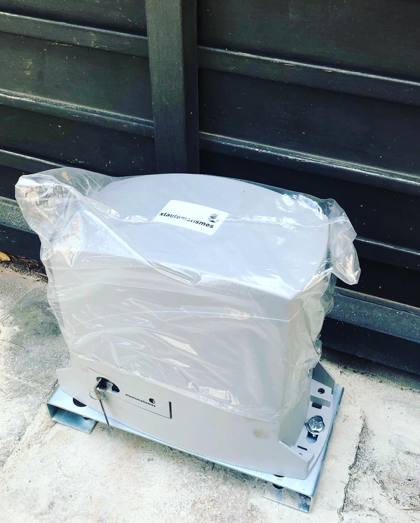 Un motor de puerta corrediza está envuelto en plástico y colocado en el suelo.