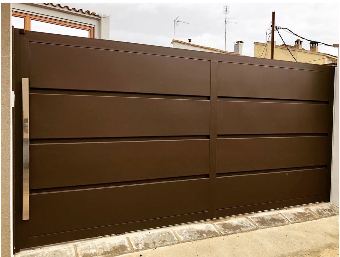 Una puerta de metal marrón con manija de acero inoxidable se encuentra encima de una pared de piedra.