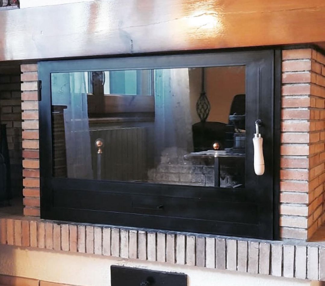 Una chimenea con puerta de cristal y tirador de madera