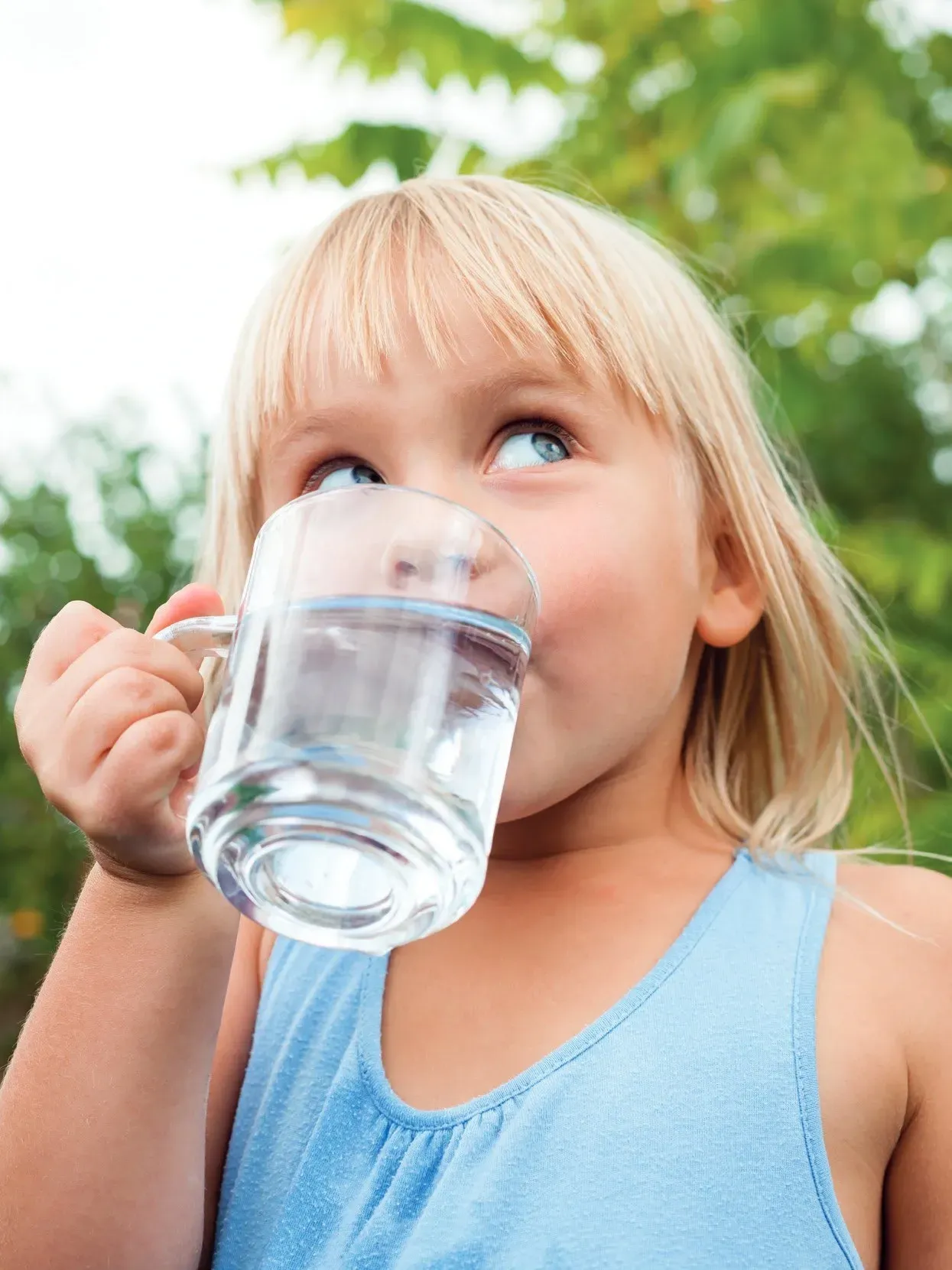 Una niña está bebiendo agua de un vaso.