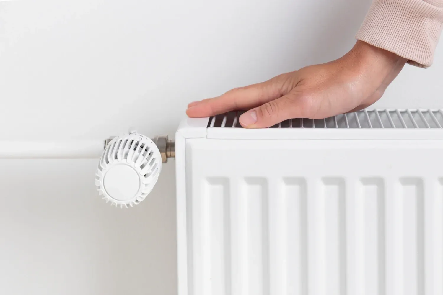 Una persona está ajustando el termostato de un radiador.