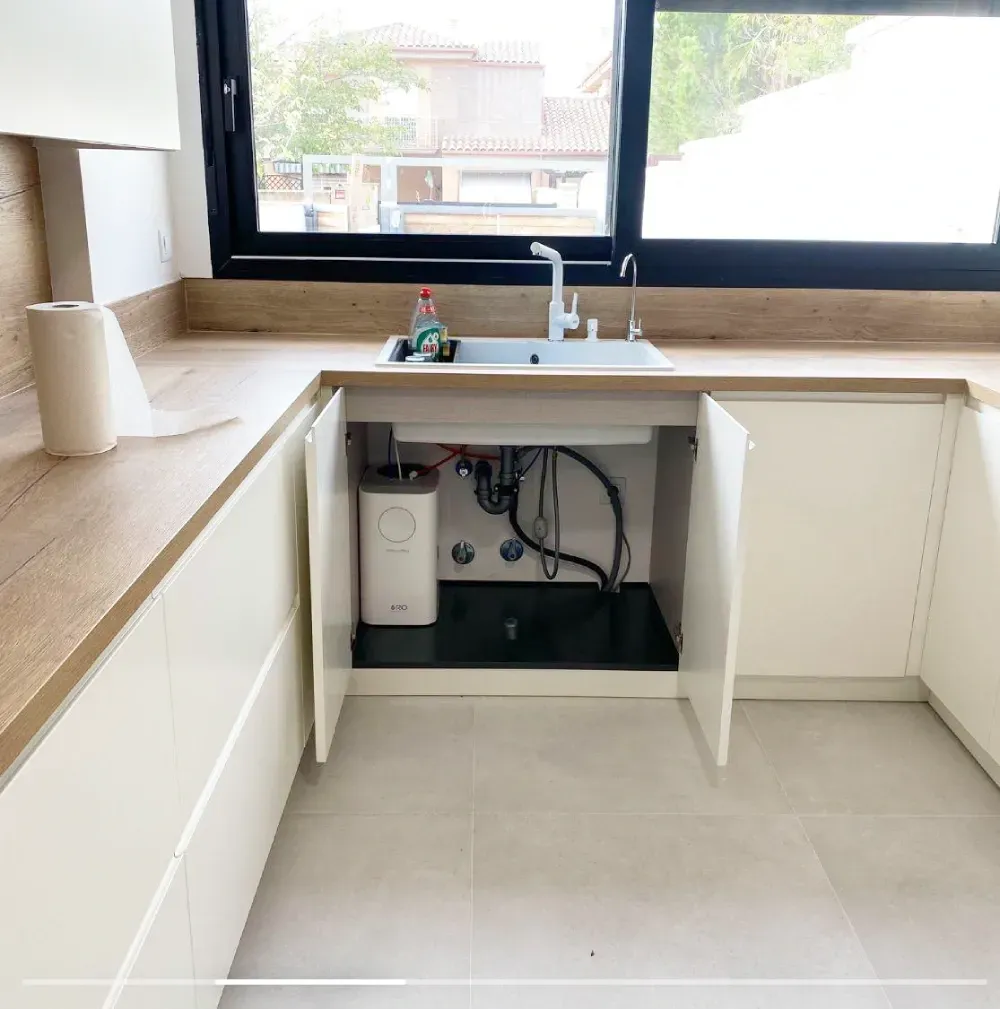 Una cocina con un fregadero debajo de un armario y una ventana.