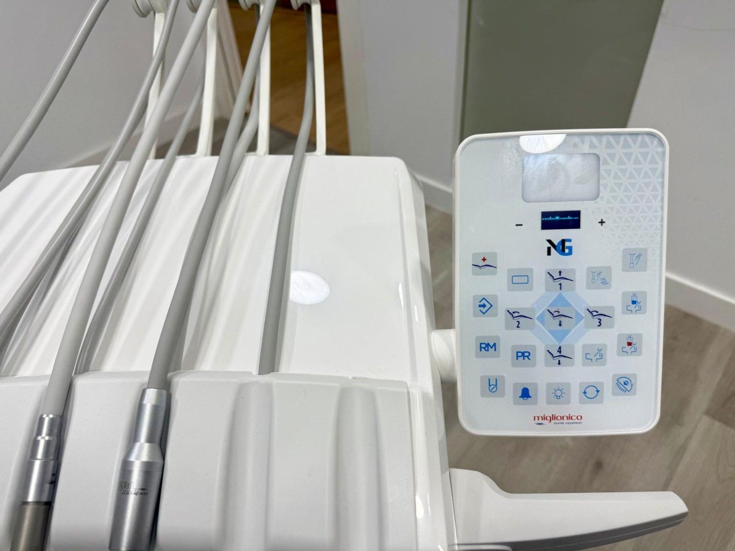 Máquina de ultrasonido dental con piezas de mano blancas y un panel de control con botones y pantalla.