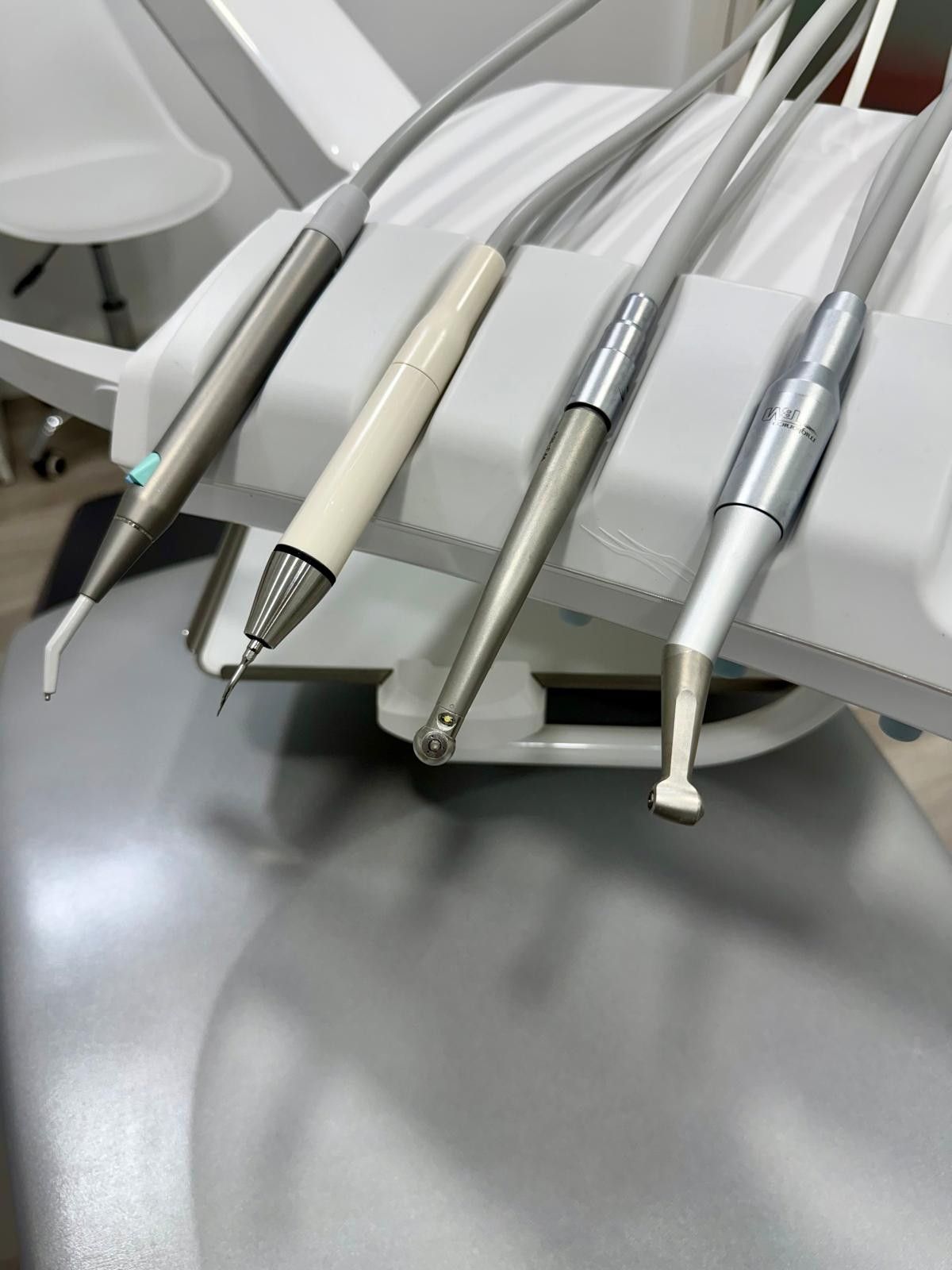 Instrumentos dentales en una bandeja, con varios instrumentos de metal y mango blanco dispuestos en un entorno clínico.