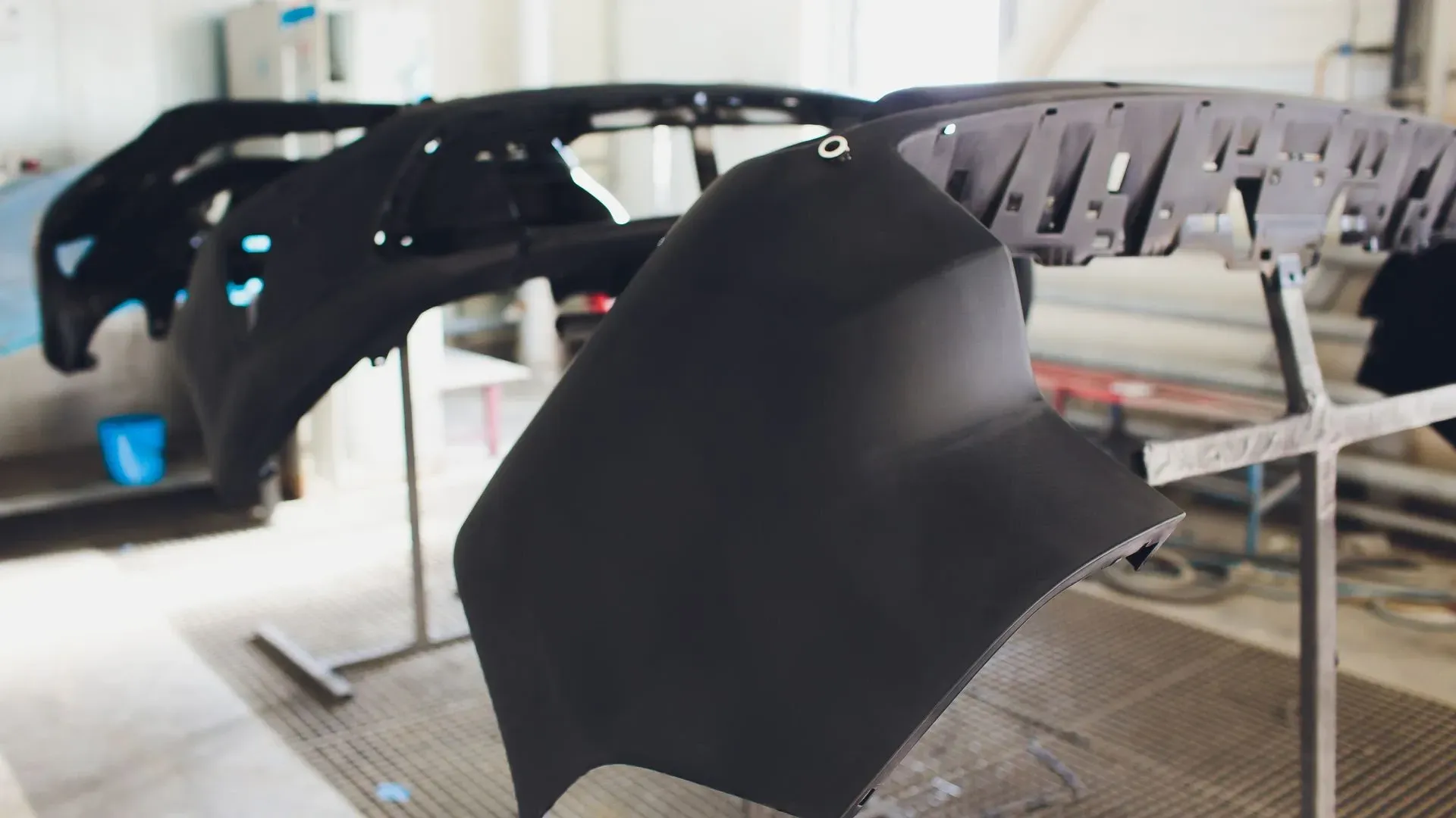 Parachoques de automóviles negros sobre soportes en un taller.