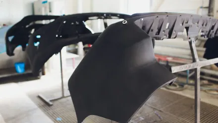 Parachoques de automóviles negros sobre soportes en un taller.